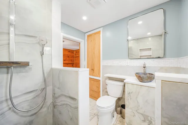 a bathroom with a granite countertop toilet sink and mirror