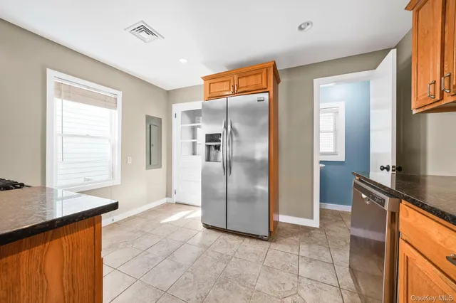 a view of a refrigerator in kitchen and an empty room