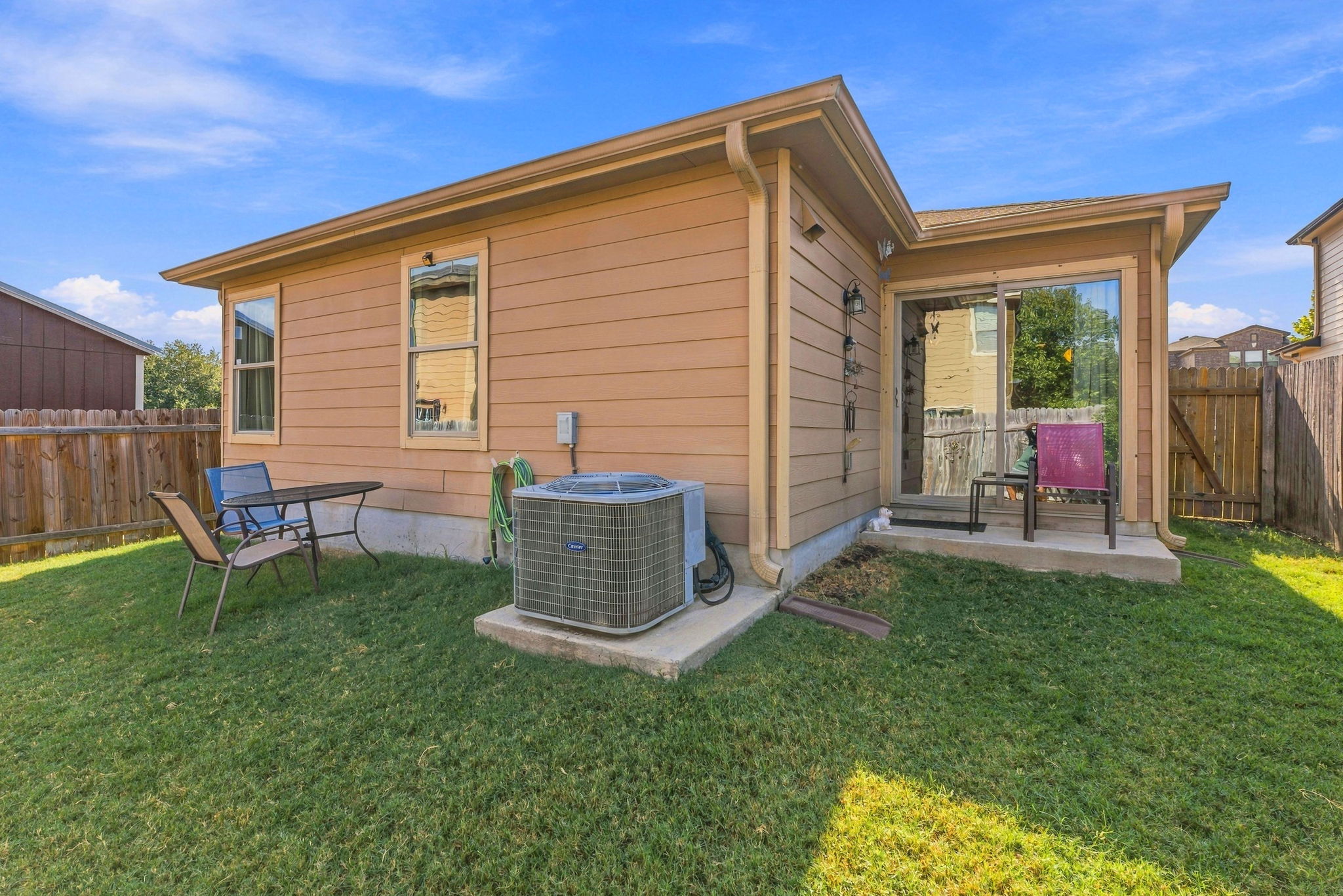 9004 Wiley Way Austin, TX 78747 - Photo 27 of 39 A grassy backyard features horizontal siding and sliding glass doors leading inside.
