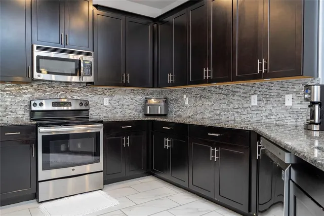 a kitchen with granite countertop a stove and a microwave