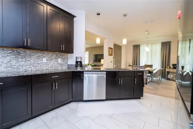 a kitchen with stainless steel appliances granite countertop a sink and a refrigerator