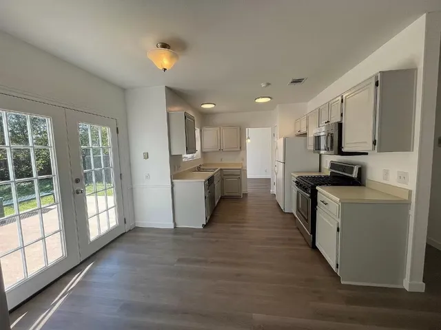 a kitchen with stainless steel appliances kitchen island granite countertop a stove a sink dishwasher and a refrigerator with wooden floor