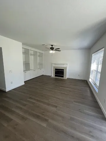 an empty room with wooden floor fireplace and windows