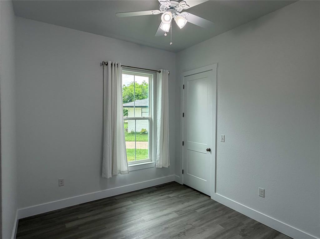4200 Williams Road Bellmead, TX 76705 - Photo 12 of 22 an empty room with wooden floor fan and windows