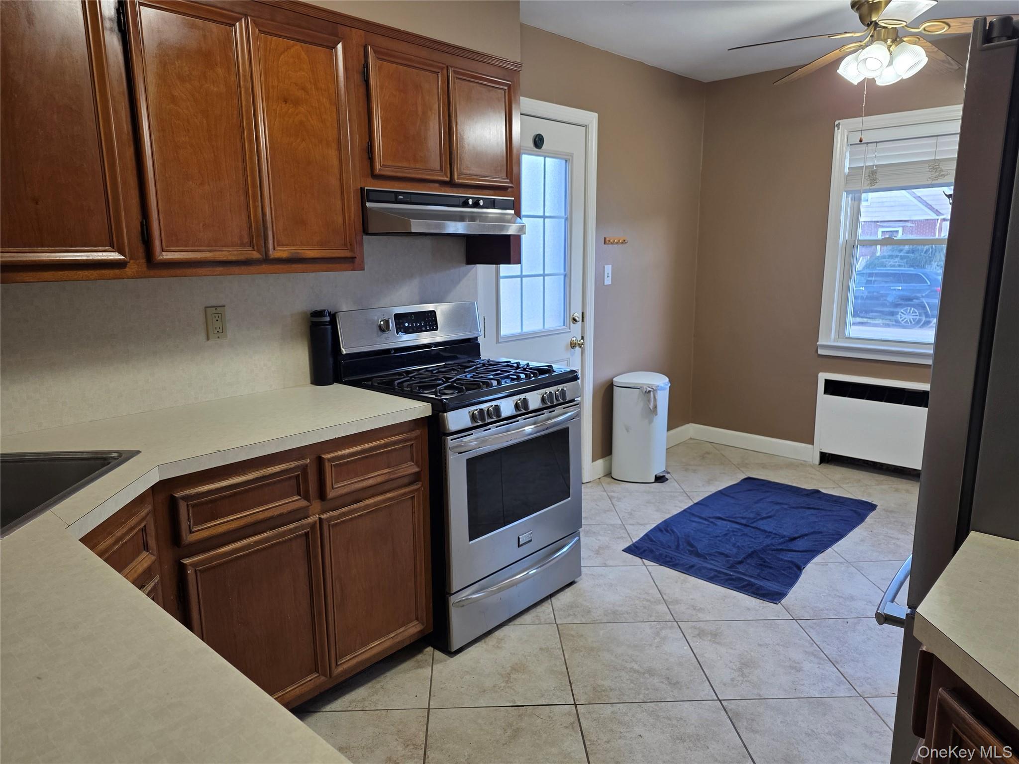 220 Raff Avenue Mineola, NY 11501 - Photo 4 of 22 Kitchen featuring gas range, light countertops, radiator, a ceiling fan, and light tile patterned flooring