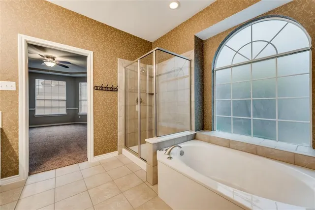 a bathroom with a tub a mirror and a shower