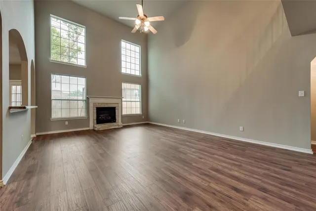 an empty room with wooden floor fireplace and windows