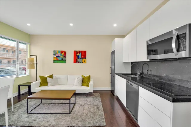 a living room with stainless steel appliances kitchen island granite countertop a sink and a stove top oven