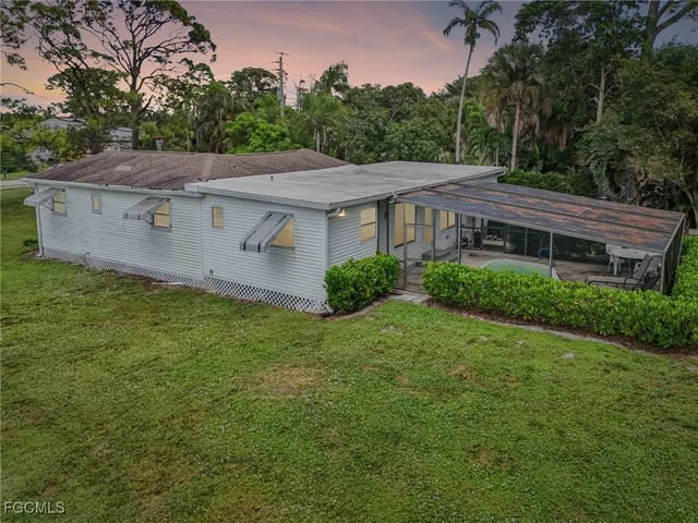 a view of a house with a big yard plants and large tree