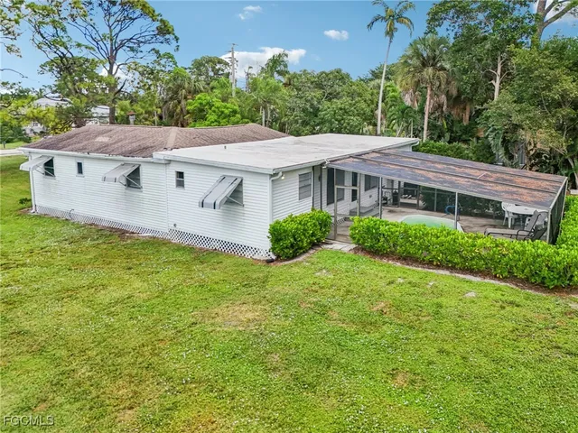 a view of a house with a yard plants and large tree