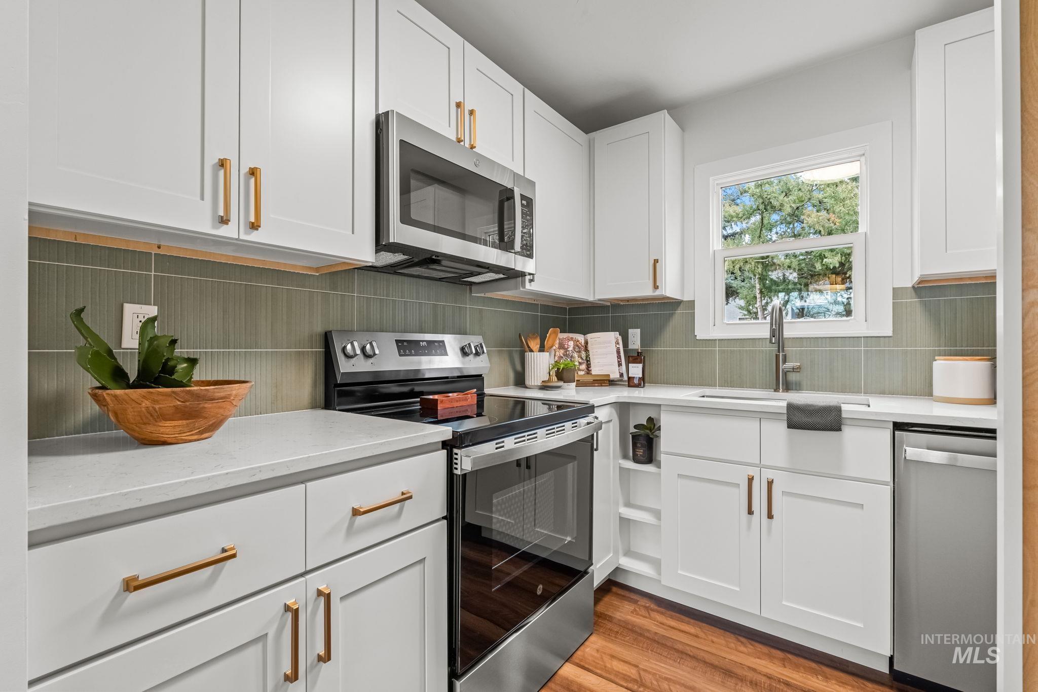 5420 Anna Street Boise, ID 83705 - Photo 12 of 24 Kitchen with stainless steel appliances, white cabinetry, light stone countertops, light wood finished floors, and tasteful backsplash