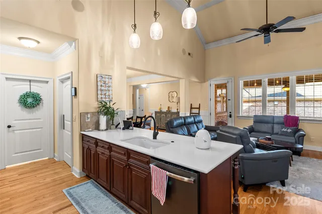 a living room with stainless steel appliances kitchen island granite countertop a sink a stove and a dining table with wooden floor