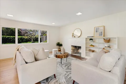 a living room with furniture a fireplace and a large window