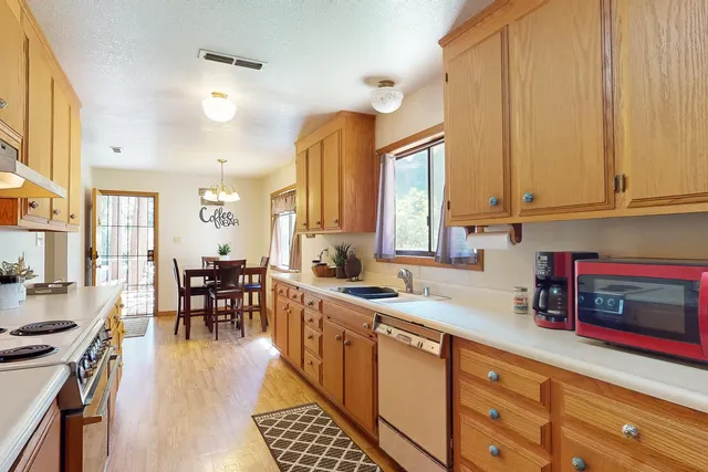 a kitchen with stainless steel appliances granite countertop a stove a sink a dining table and chairs with wooden floor