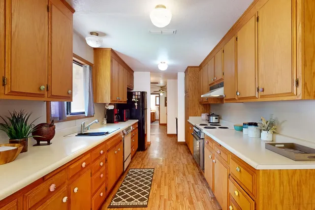 a kitchen with stainless steel appliances granite countertop a sink a stove cabinets counter space and a window