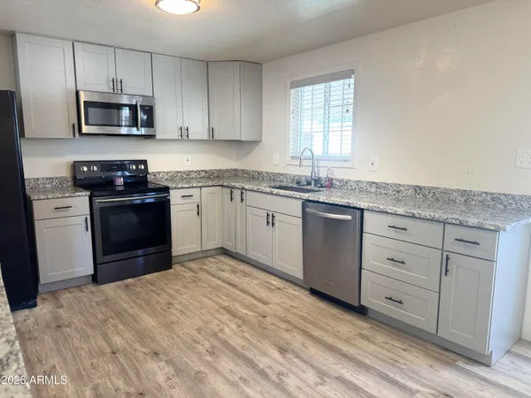 a kitchen with granite countertop white cabinets and stainless steel appliances