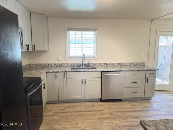 a white kitchen with granite countertop white cabinets and a sink