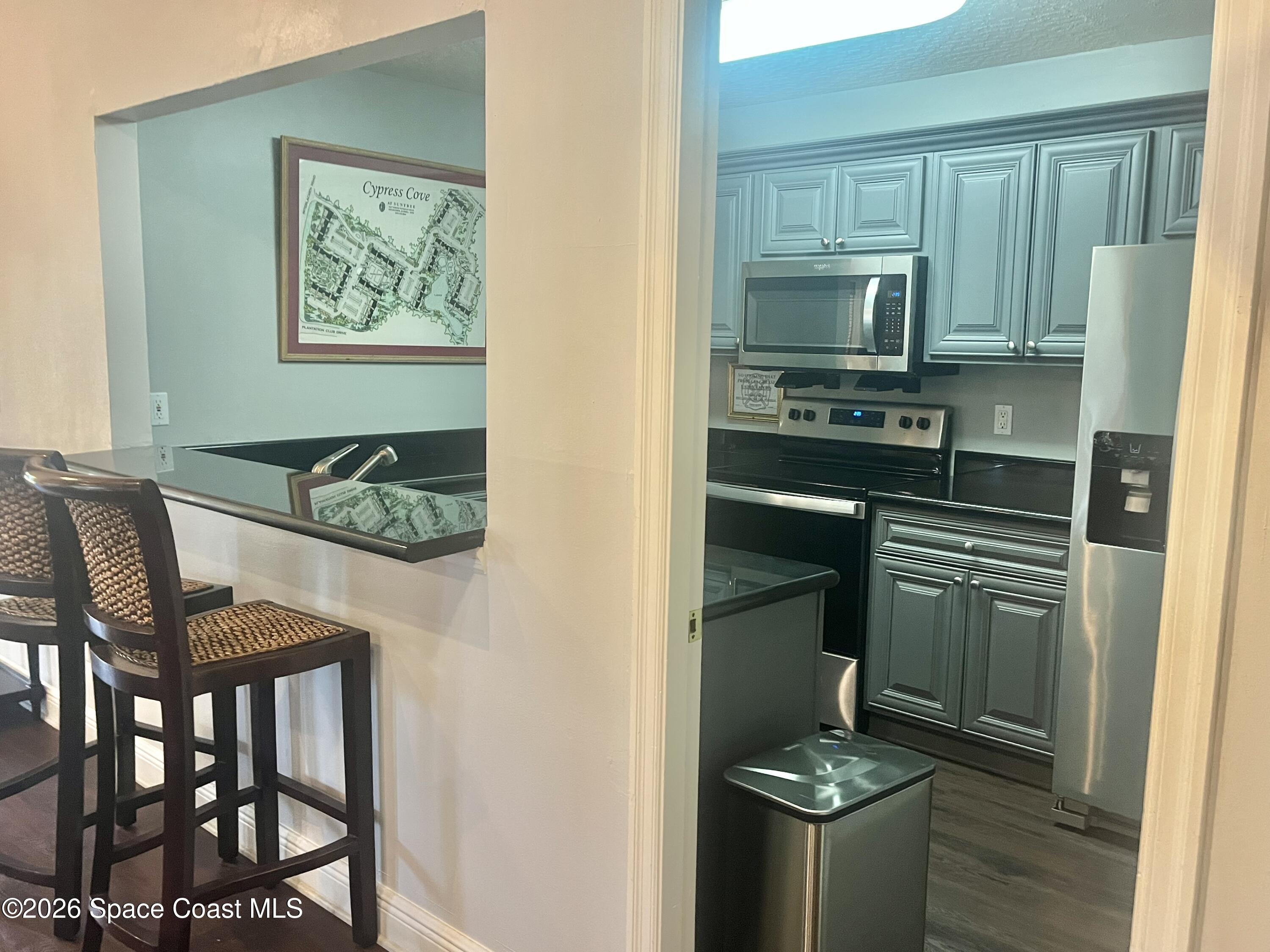 7667 North Wickham Road, Unit 1118 Melbourne, FL 32940 - Photo 24 of 26 a kitchen with stainless steel appliances granite countertop a stove refrigerator and a microwave