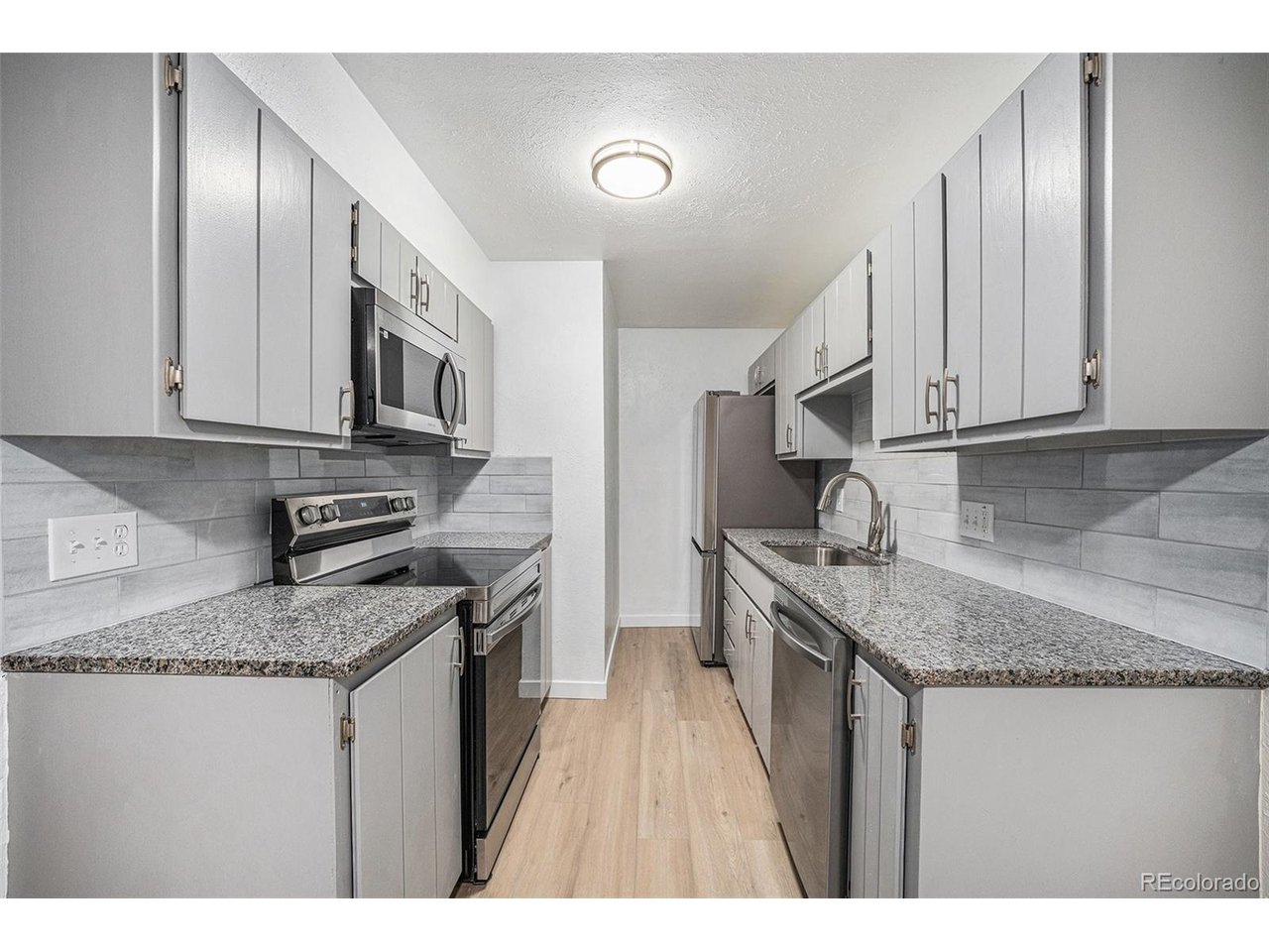 a kitchen with stainless steel appliances granite countertop a sink stove and refrigerator