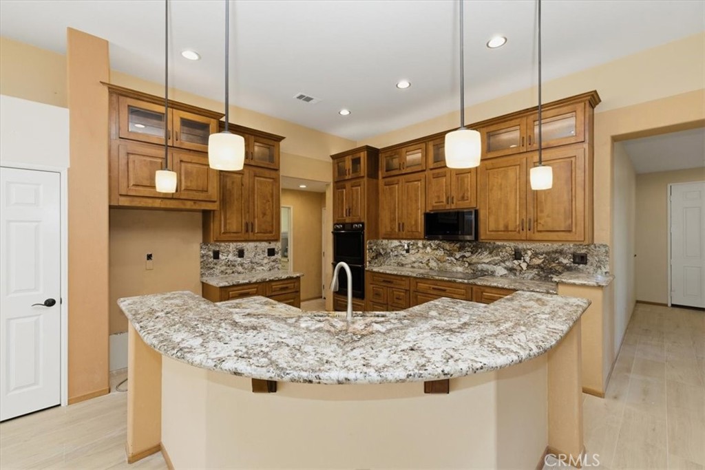 13747 Robinbrook Court Eastvale, CA 92880 - Photo 19 of 50 a kitchen with kitchen island granite countertop wooden floor and a view of living room