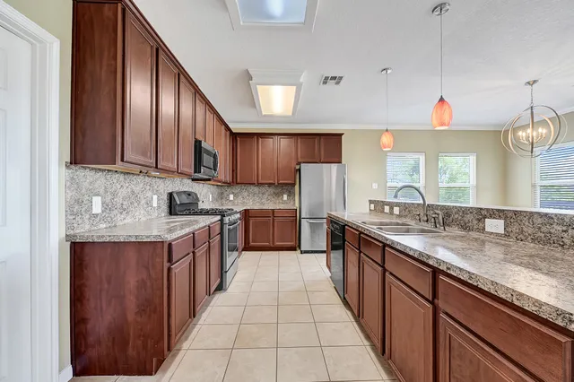 a large kitchen with stainless steel appliances granite countertop a sink counter space cabinets and a large window