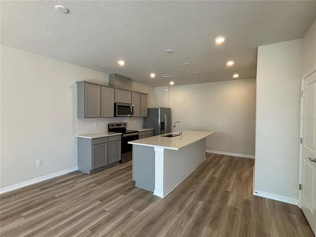 a kitchen with a sink wooden floor and stainless steel appliances