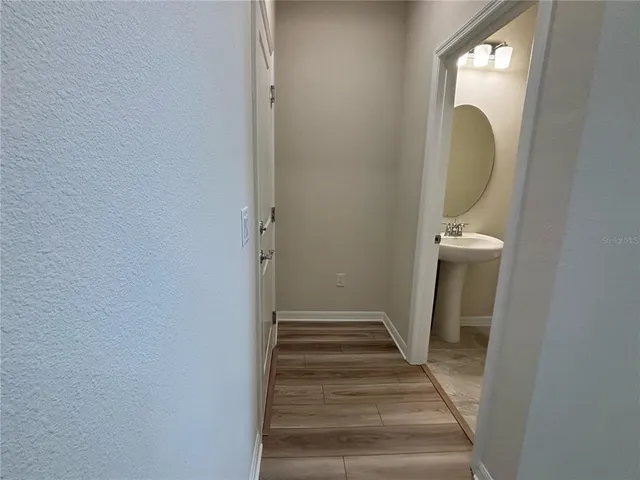 a view of a hallway with wooden floor and a bathroom