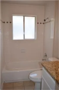 a bathroom with a granite countertop sink a toilet and shower