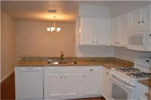 a kitchen with granite countertop white cabinets and white appliances