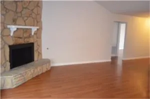 a view of empty room with wooden floor and fireplace