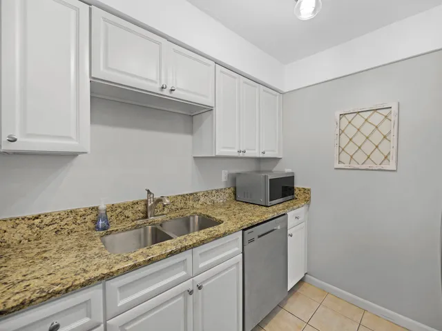 a kitchen with stainless steel appliances granite countertop white cabinets and a sink