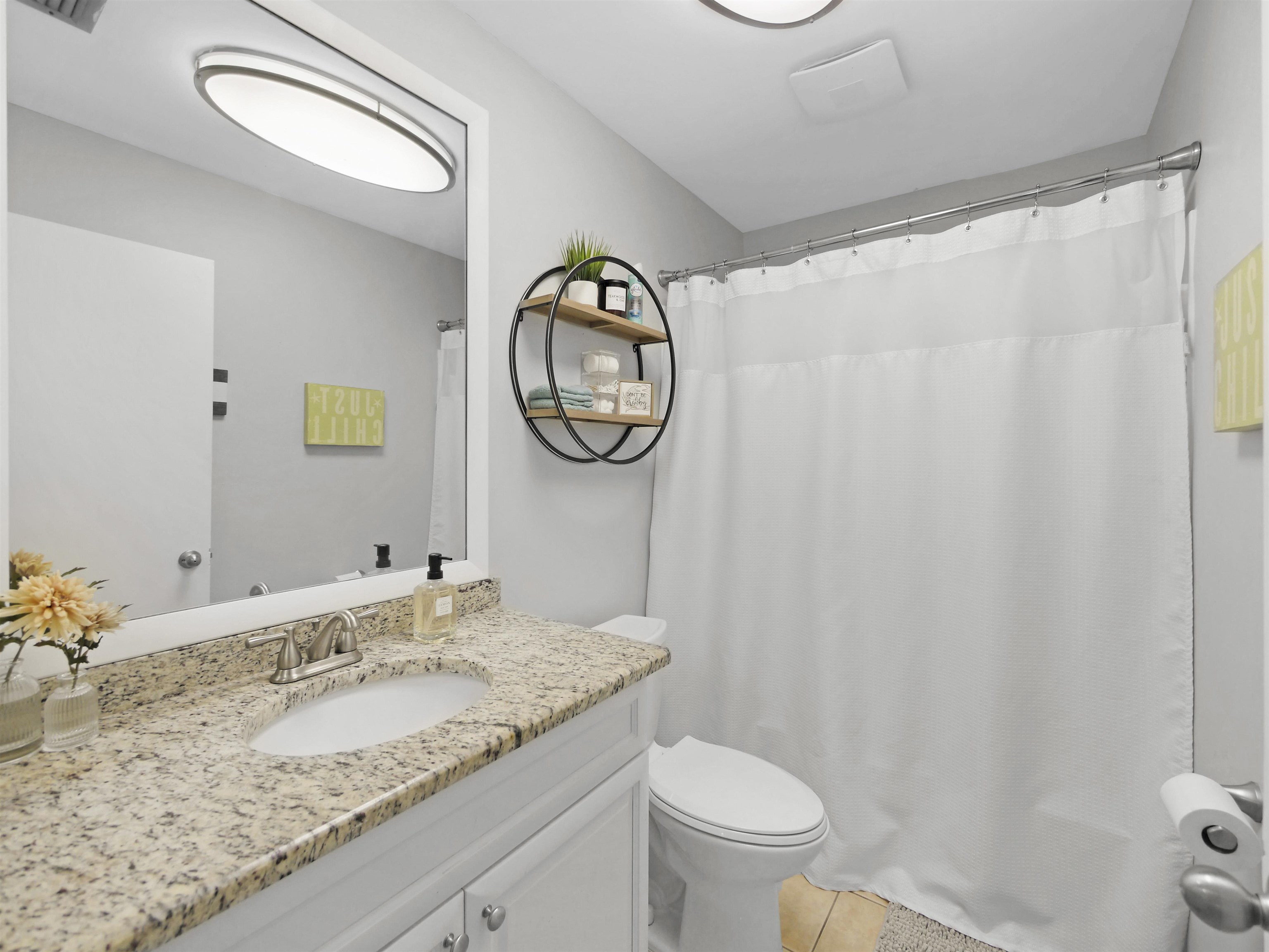 129 Rio Del Mar Street, Unit C St. Augustine, FL 32080 - Photo 16 of 26 a bathroom with a granite countertop sink and a mirror