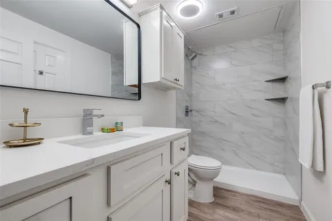 a bathroom with a granite countertop sink toilet and shower