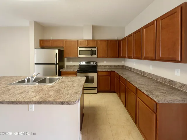 a kitchen with kitchen island granite countertop a sink a counter top space appliances and cabinets