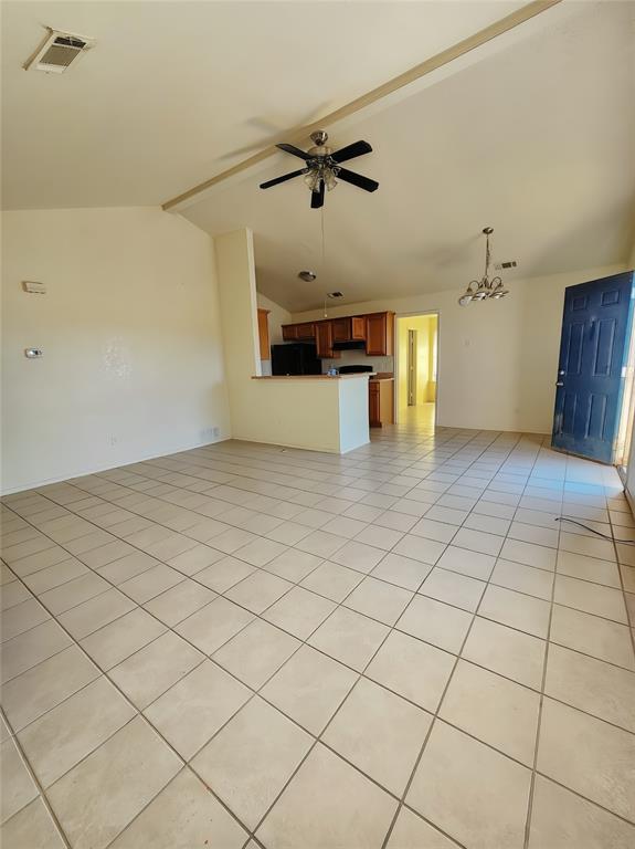 Unfurnished living room with light tile patterned flooring, vaulted ceiling, ceiling fan, and a chandelier