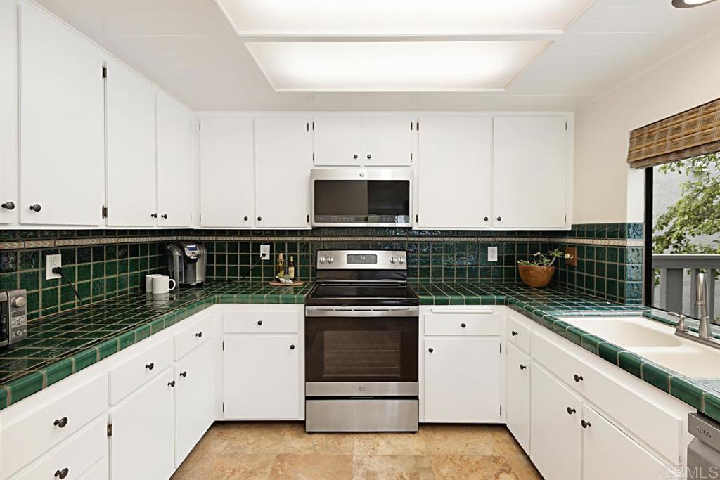 3242 Via Alicante La Jolla, CA 92037 - Photo 9 of 27 a kitchen with granite countertop white cabinets and white appliances