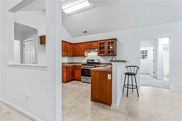 a kitchen with stainless steel appliances granite countertop a stove top oven a sink a counter space and cabinets