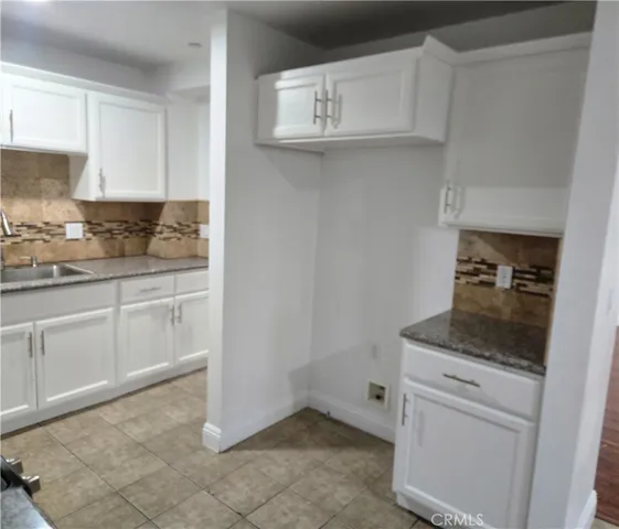 a kitchen with white cabinets and sink