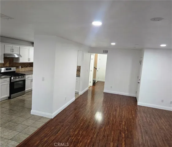 a view of a kitchen with a fridge and wooden floor