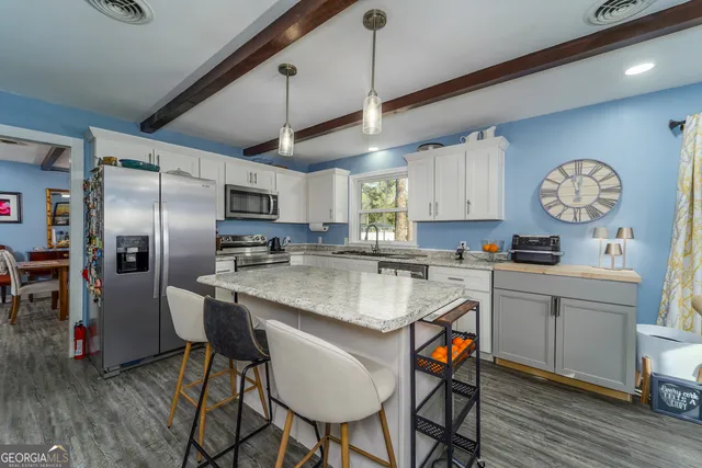 a kitchen with stainless steel appliances granite countertop a sink a stove a refrigerator cabinets and chairs