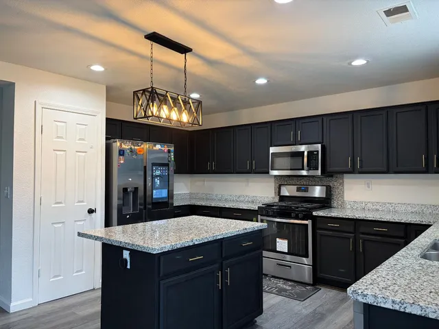 a kitchen with kitchen island granite countertop stainless steel appliances a stove sink microwave and cabinets