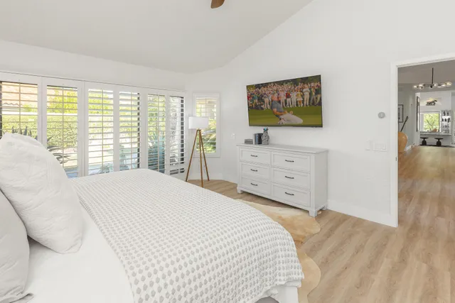 a bedroom with a large bed and a flat tv screen on dresser