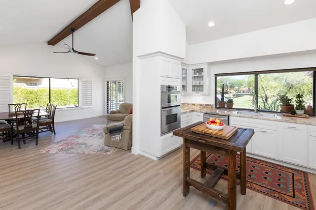 a kitchen with stainless steel appliances a table chairs refrigerator and cabinets