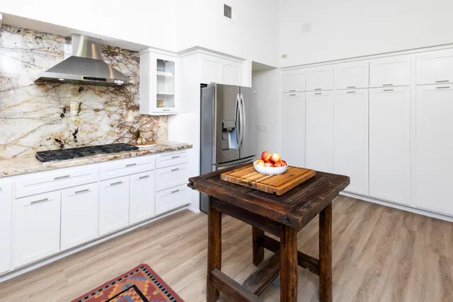 a kitchen with stainless steel appliances kitchen island a table chairs in it and wooden floors