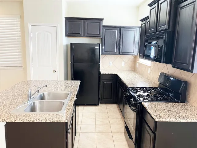 a kitchen with granite countertop a sink a stove and refrigerator