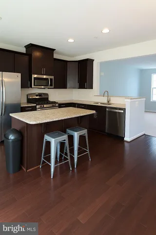 a kitchen with stainless steel appliances granite countertop a table chairs sink and wooden floor
