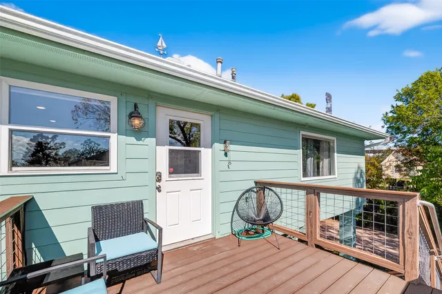 a front view of a house with wooden deck and furniture