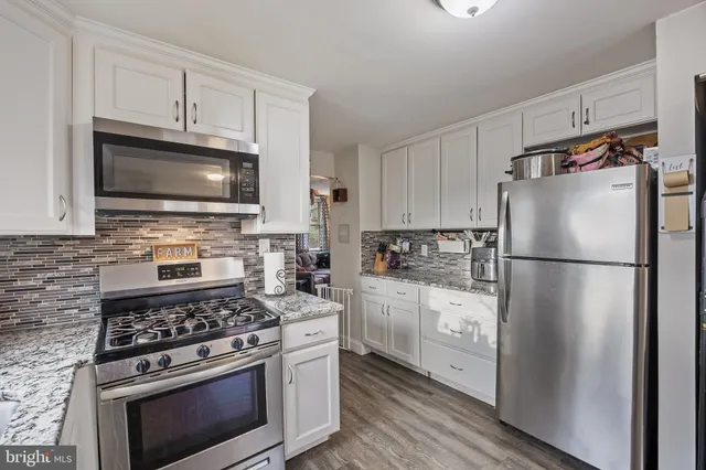 a kitchen with cabinets stainless steel appliances and wooden floor
