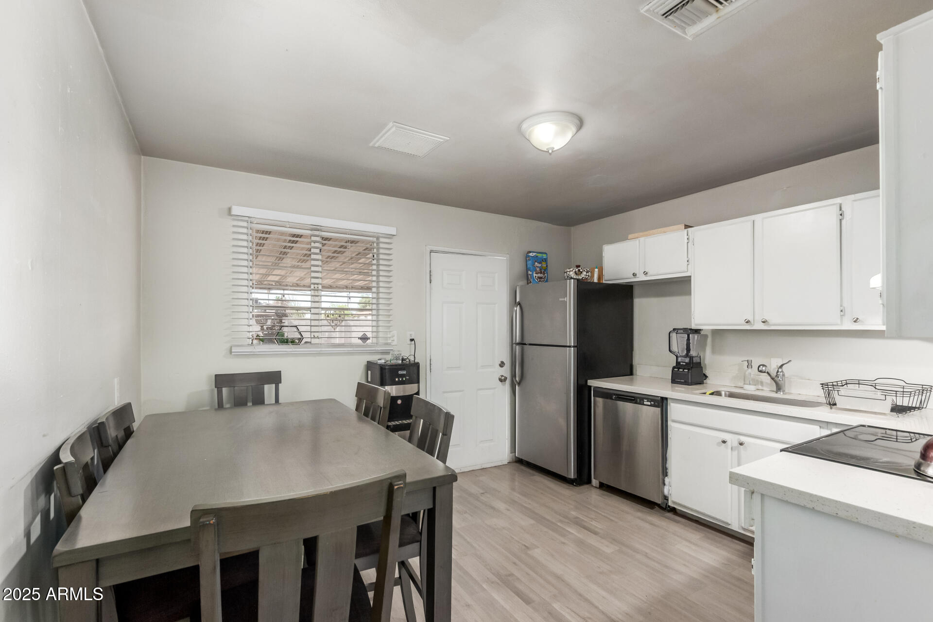 2752 West Royal Palm Road Phoenix, AZ 85051 - Photo 10 of 23 a kitchen with stainless steel appliances a sink a stove a refrigerator with white cabinets and wooden floor
