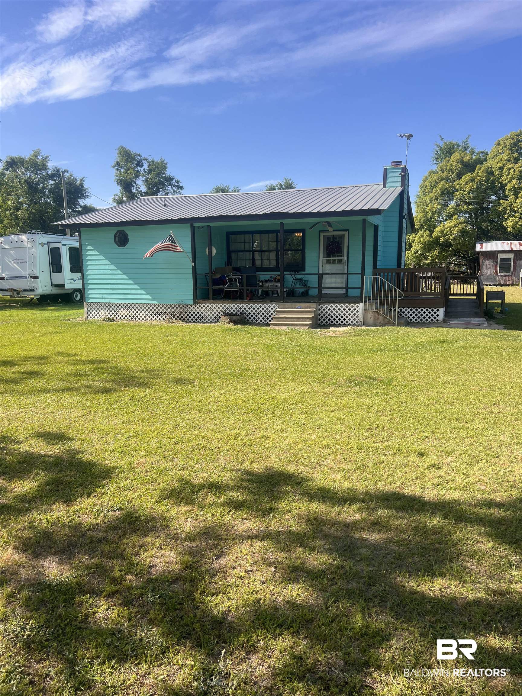 20925 Brinks Willis Road Foley, AL 36535 - Photo 1 of 9 Back of house with a deck, a metal roof, a lawn, and a chimney